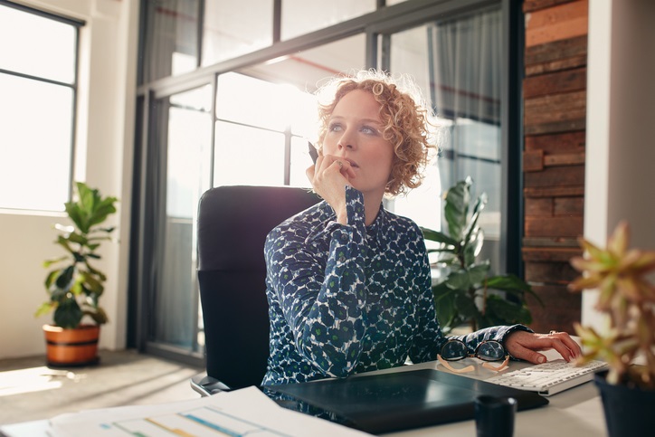 A lady sitting at a desk looking into the distance