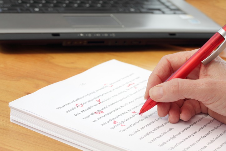 A person who is writing on a piece of paper with a red pen